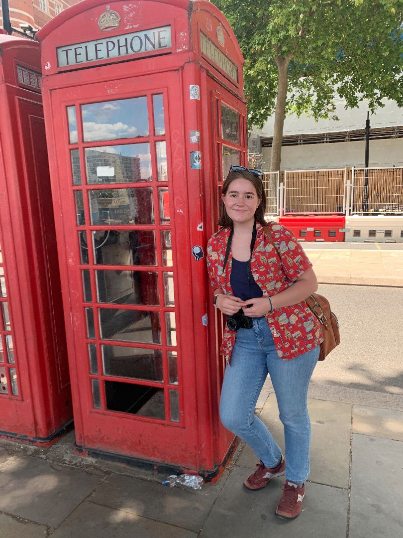 Female student leaning against telephone booth